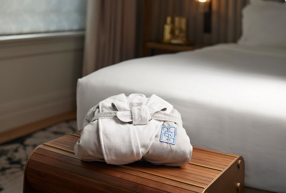 A folded white bathrobe with the hotel logo on the chest