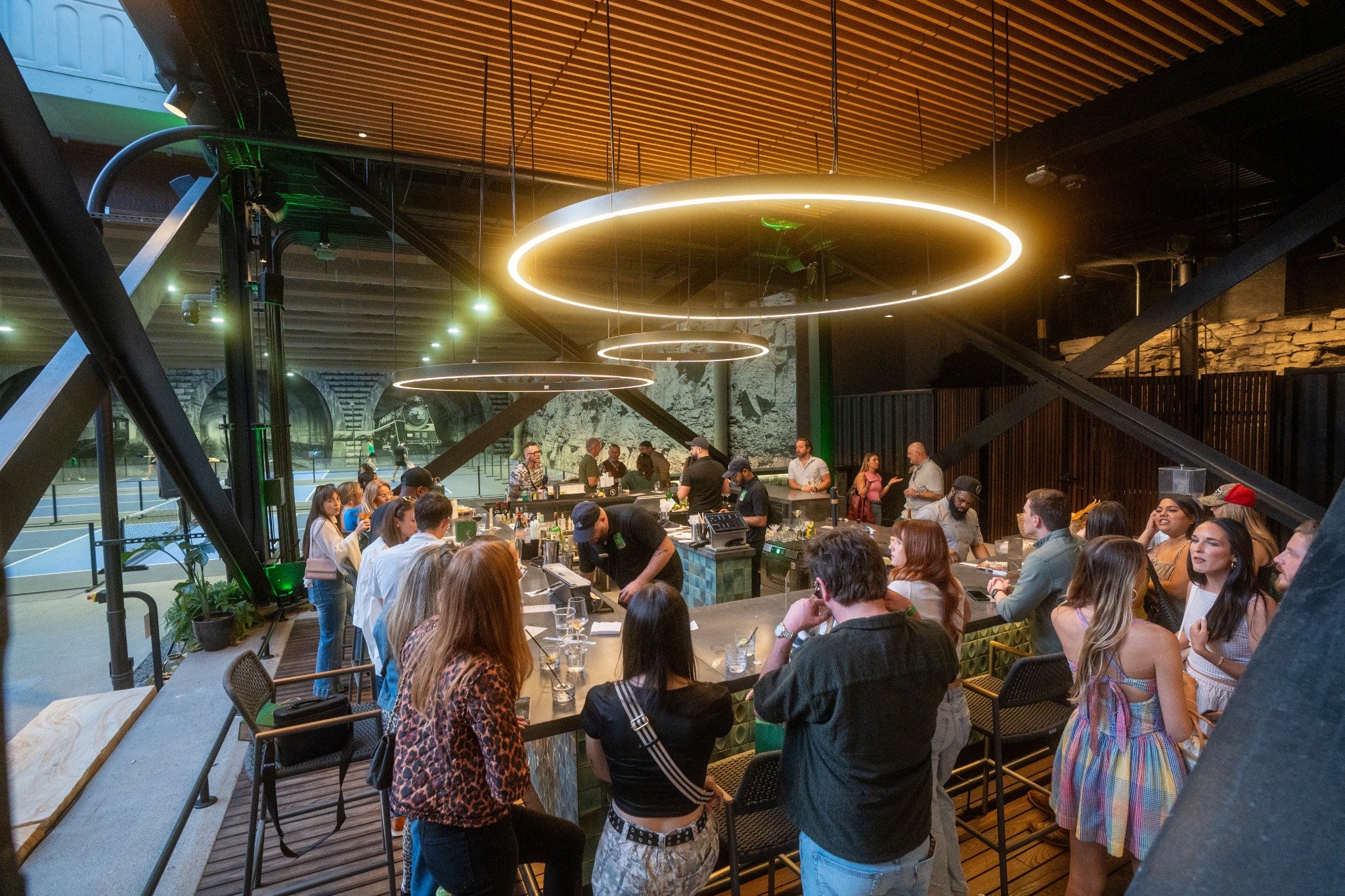 Alligator Bar Nashville under Broadway Bridge at The Union Station Nashville Yards;Open-air bar in Nashville Yards with cocktails and live music;Guests enjoying drinks at Alligator Bar Nashville outdoor space