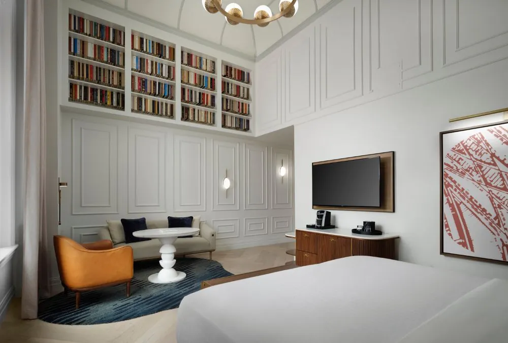 Hotel room featuring a comfortable double bed, a wall-mounted television, and a cozy seating area
