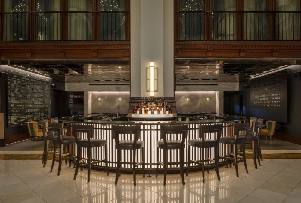 Hotel bar area with a semi-circular counter surrounded by bar stools.